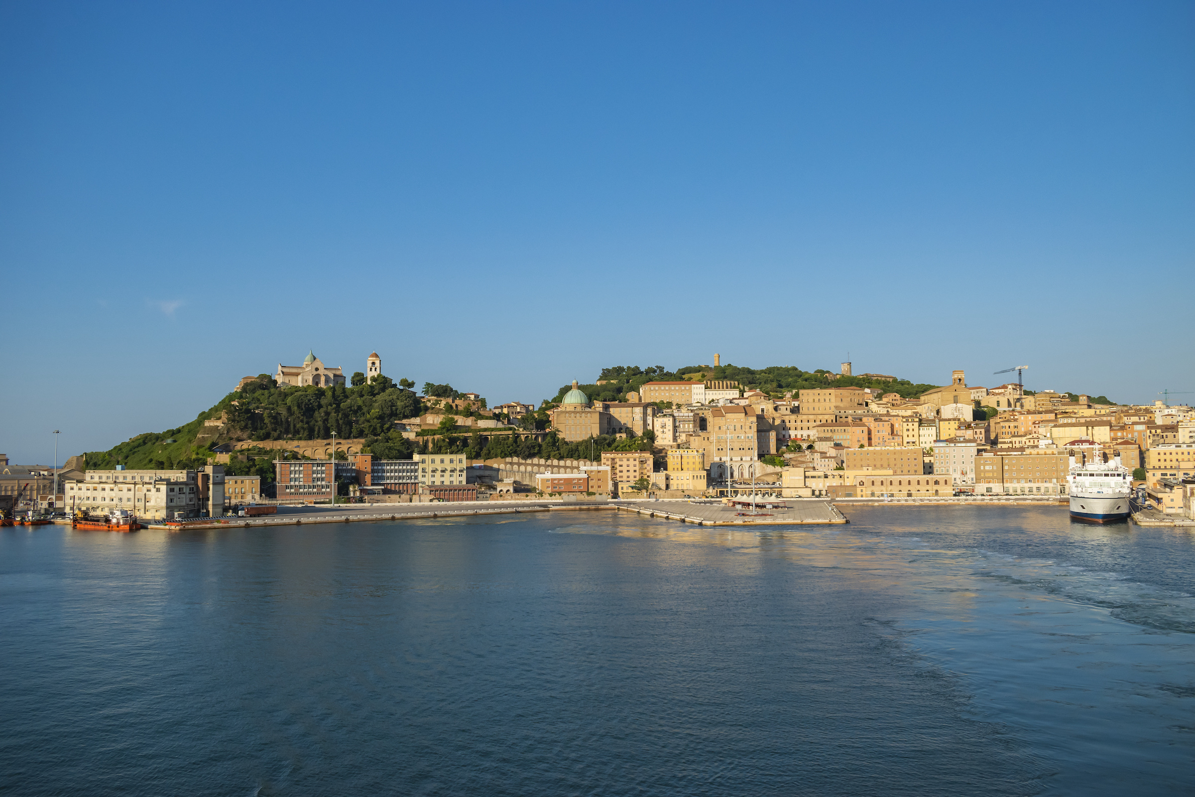 Blick vom Meer auf Hafen und Altstadt von Ancona, mit der Kathedrale San Ciriaco hoch über der Stadt. Von hier aus startet deine Überfahrt nach Patras.
